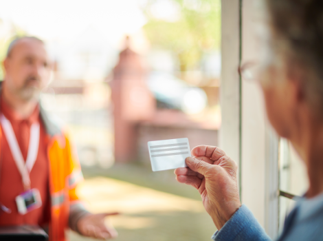 Person looking at a door-to-door salesperson's card while the salesperson stands outside