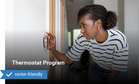 a woman changing a thermostat on a white wall